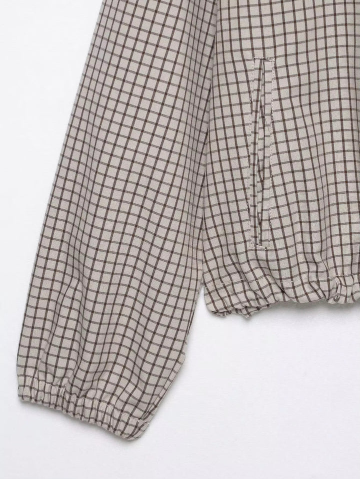 Detail von Ärmel und Saum: Gummibündchen am Ärmelende, seitliche Eingriffstasche und gerafftes Saumband der karierten Jacke auf weißem Grund. 8