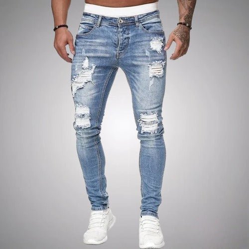 Frontansicht der zerrissenen Slim-Fit-Jeans in hellem, ausgewaschenem Blau, getragen mit weißen Sneakern, mit Rissen an Oberschenkeln und Knien. 2