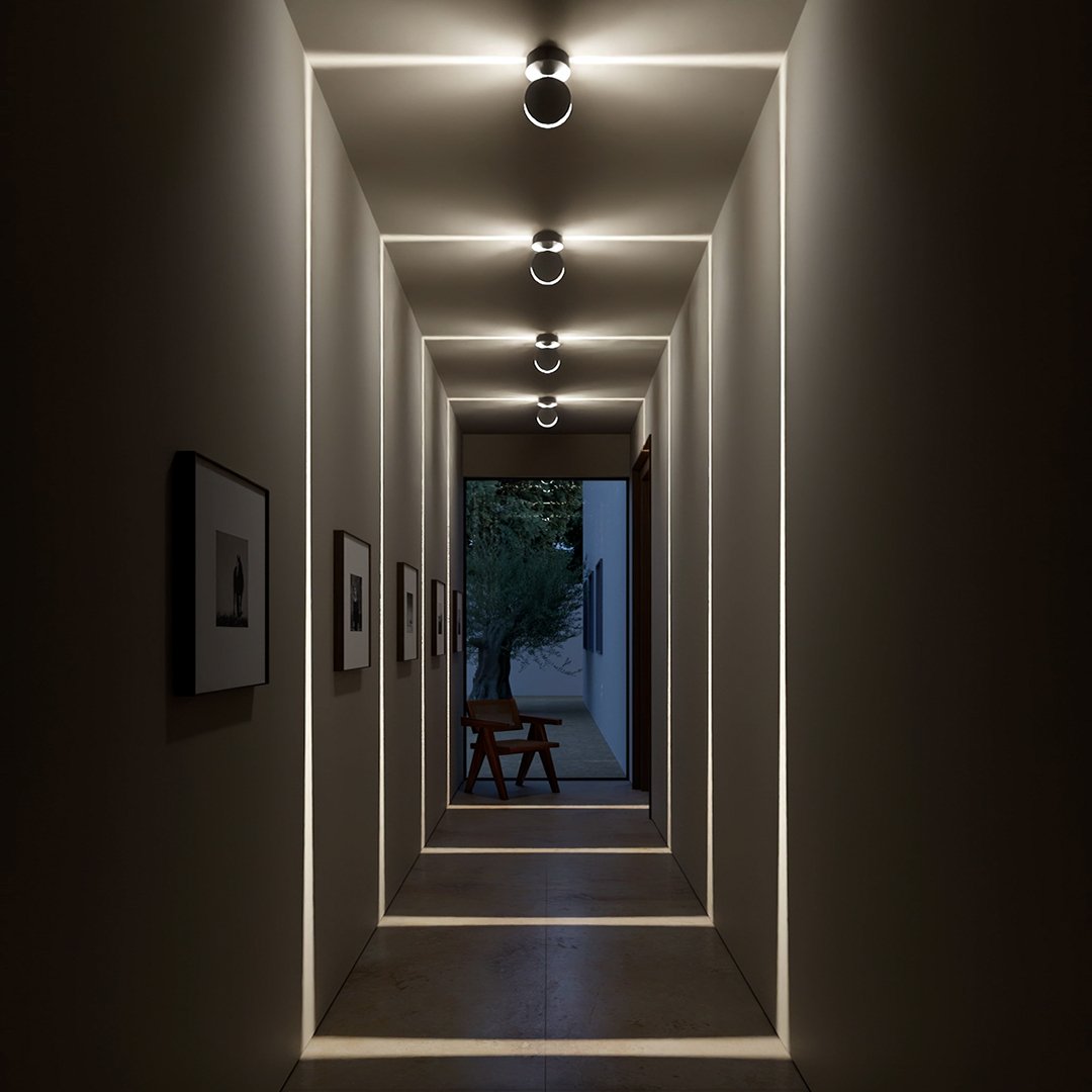 Abendliche Flurszene mit abgedunkeltem Raum, in dem die Leuchten leuchtende quadratische Lichtlinien an Wände und Boden projizieren. 8