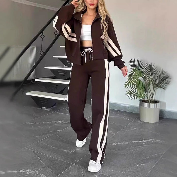 Set in Dunkelbraun mit weißen Streifen, Model geht in weißen Sneakern auf die Kamera zu, Hose mit weißer Kordel. 8