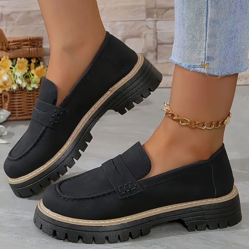 Schwarze Loafer mit beiger Zierkante an der Plateausohle, getragen mit goldener Fußkette zu Jeans. 12