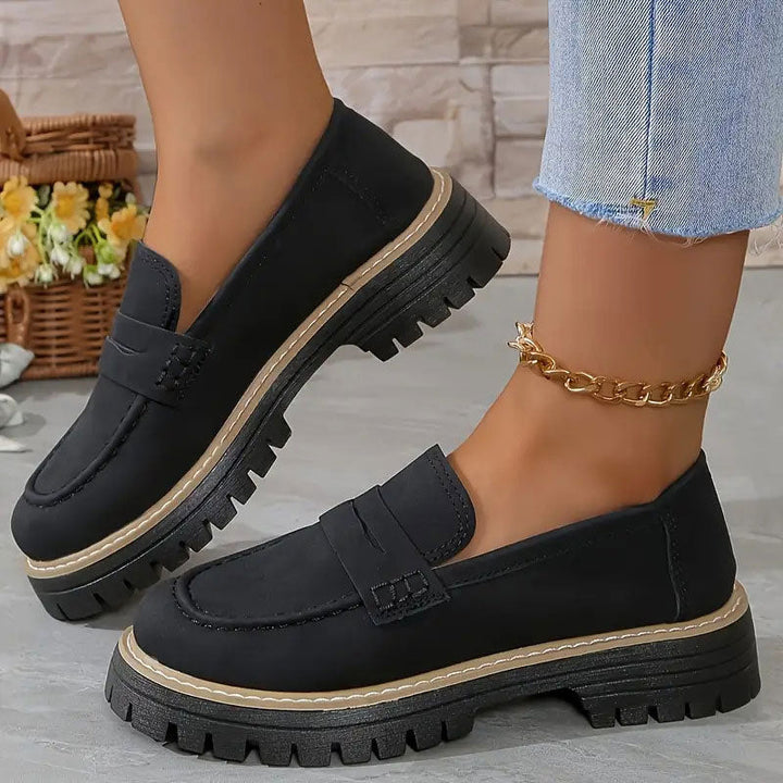 Schwarze Loafer mit beiger Zierkante an der Plateausohle, getragen mit goldener Fußkette zu Jeans. 12