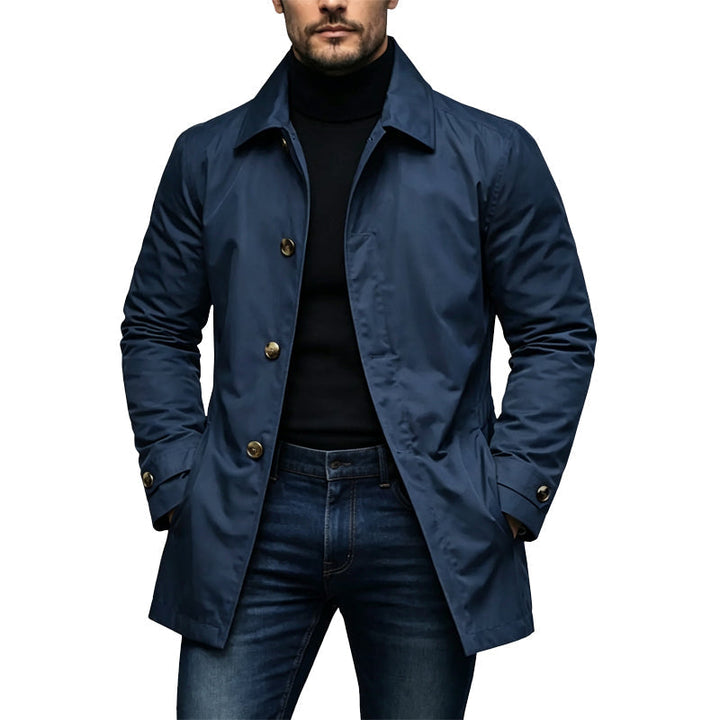 Mantel in Marineblau mit goldfarbenen Knöpfen an einem Model, getragen über schwarzem Rollkragenpullover und Jeans. 4