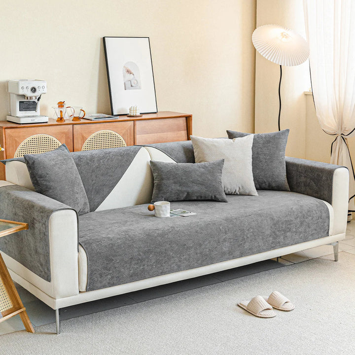Grauer Chenille-Sofabezug auf weißem Dreisitzer im Wohnzimmer, mit grauen Kissen, Kaffeetasse, Holzkommode, Stehlampe und Hausschuhen. 13