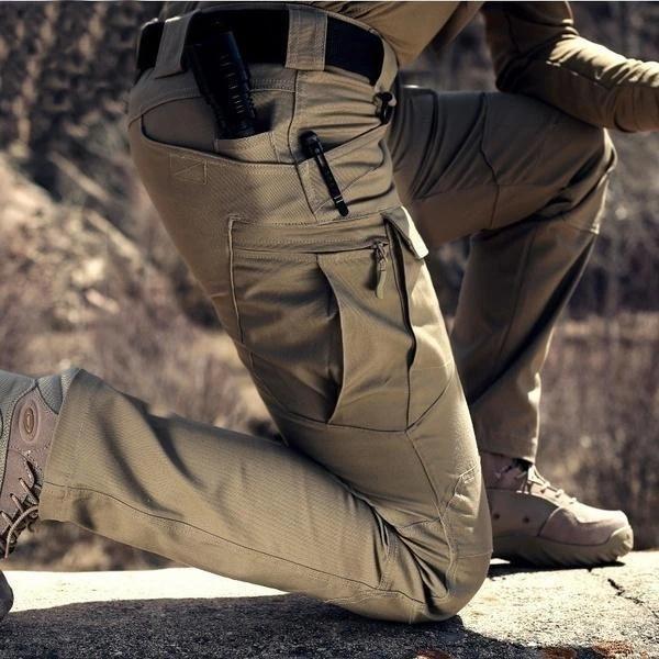 Nahaufnahme der knienden Hose im Gelände mit großer Beintasche, Reißverschluss und Gürteltaschen mit Stift 2