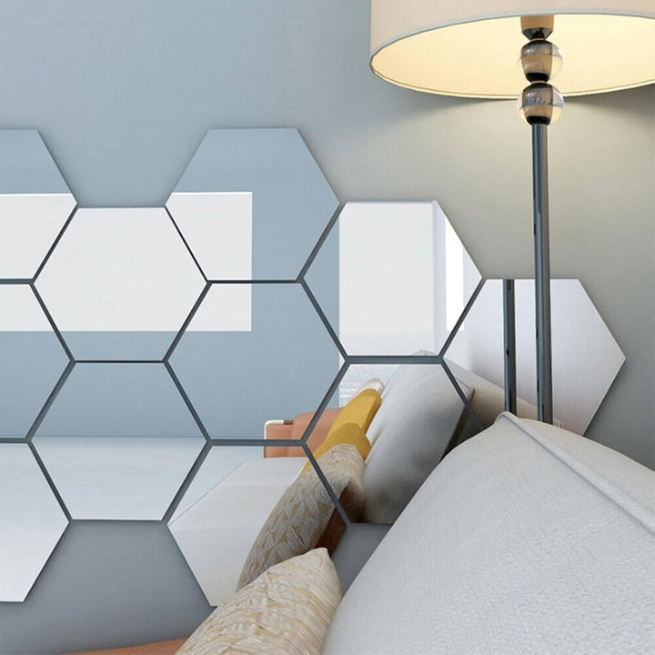 Sechseckige Spiegelflächen an einer blaugrauen Wand neben einer Stehlampe, sie spiegeln ein Sofa mit gelben und beigen Kissen. 6