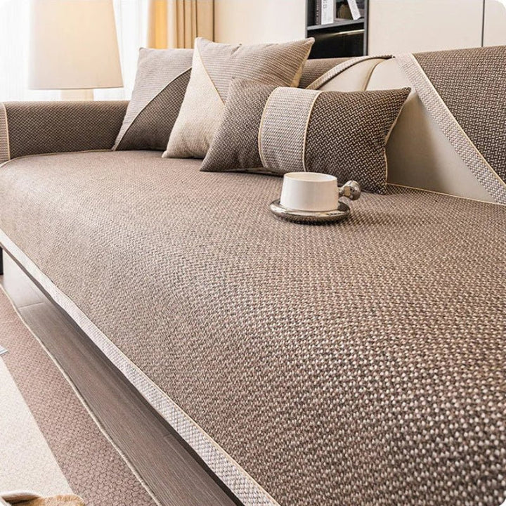 Sofabezug in Braun mit heller Zierkante auf dem Sofa, passende Kissen und Tasse auf dem Sitz. 10