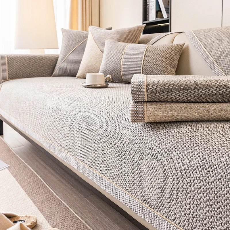 Zwei gefaltete Sofabezüge in Grau und Beige liegen auf dem beigegrauen Bezug auf dem Sofa. 6