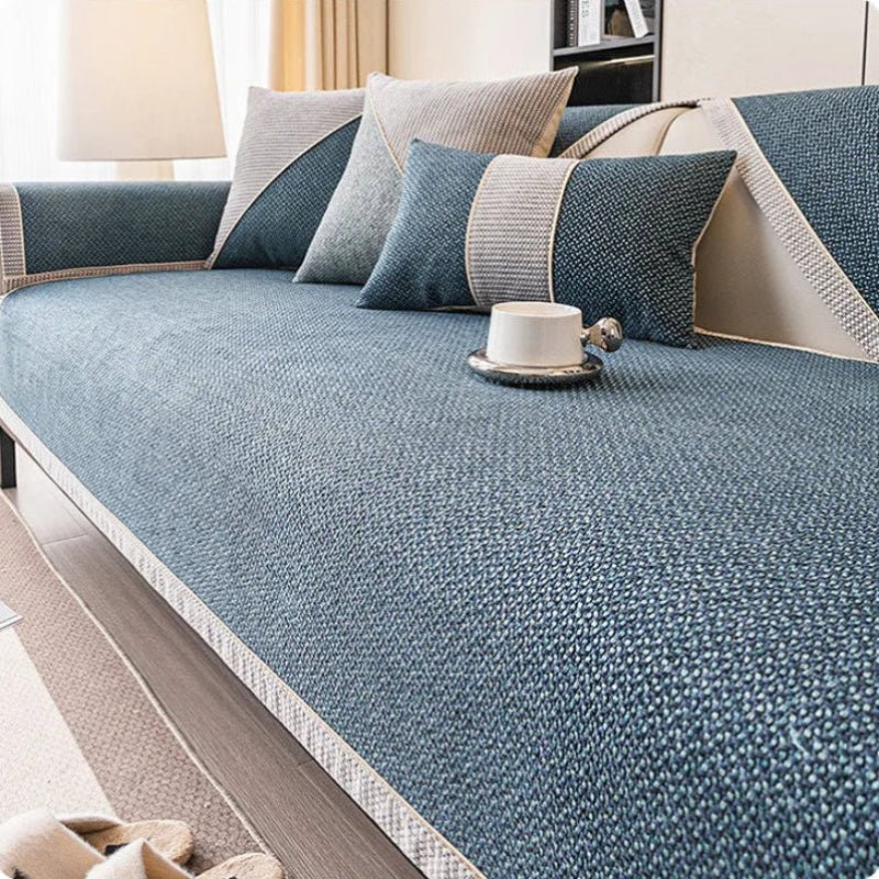 Sofabezug in Dunkelblau mit heller Zierkante auf dem Sofa, dazu blaue und graue Kissen. 8