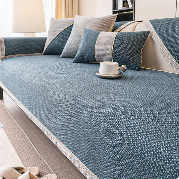 Sofabezug in Dunkelblau mit heller Zierkante auf dem Sofa, dazu blaue und graue Kissen. 8