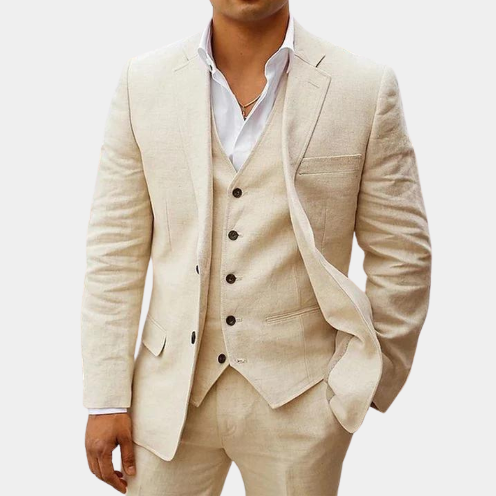 Dreiteiliger Anzug in Creme-Beige mit Weste und Hose, getragen mit weißem offenem Hemd, eine Hand in der Hosentasche. 1