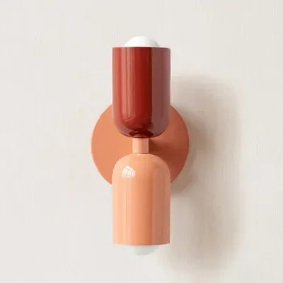 Wandlampe mit rotem oberem Schirm, lachsfarbener Wandplatte und lachsfarbenem unterem Schirm vor heller Wand. 20