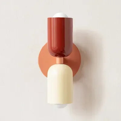 Wandlampe mit rotem oberem Schirm, lachsfarbener Wandplatte und cremefarbenem unterem Schirm vor heller Wand. 17