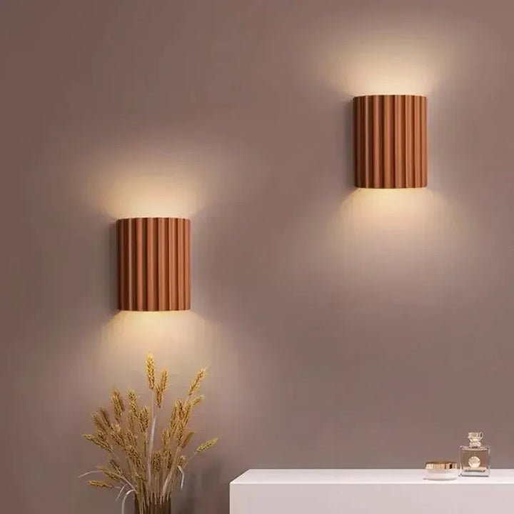 Zwei terrakottafarbene Wandlampen strahlen warmes Licht an eine mauvefarbene Wand über einer Anrichte 8