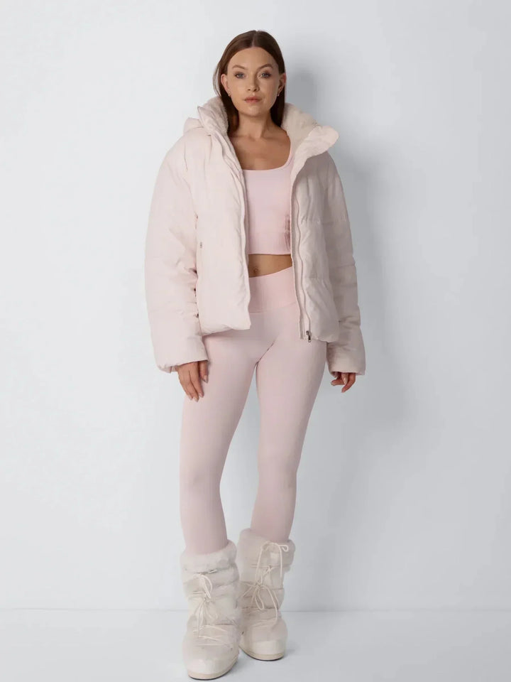Ganzkörperansicht der rosafarbenen Steppjacke, offen getragen, mit rosa Leggings und flauschigen Stiefeln 10