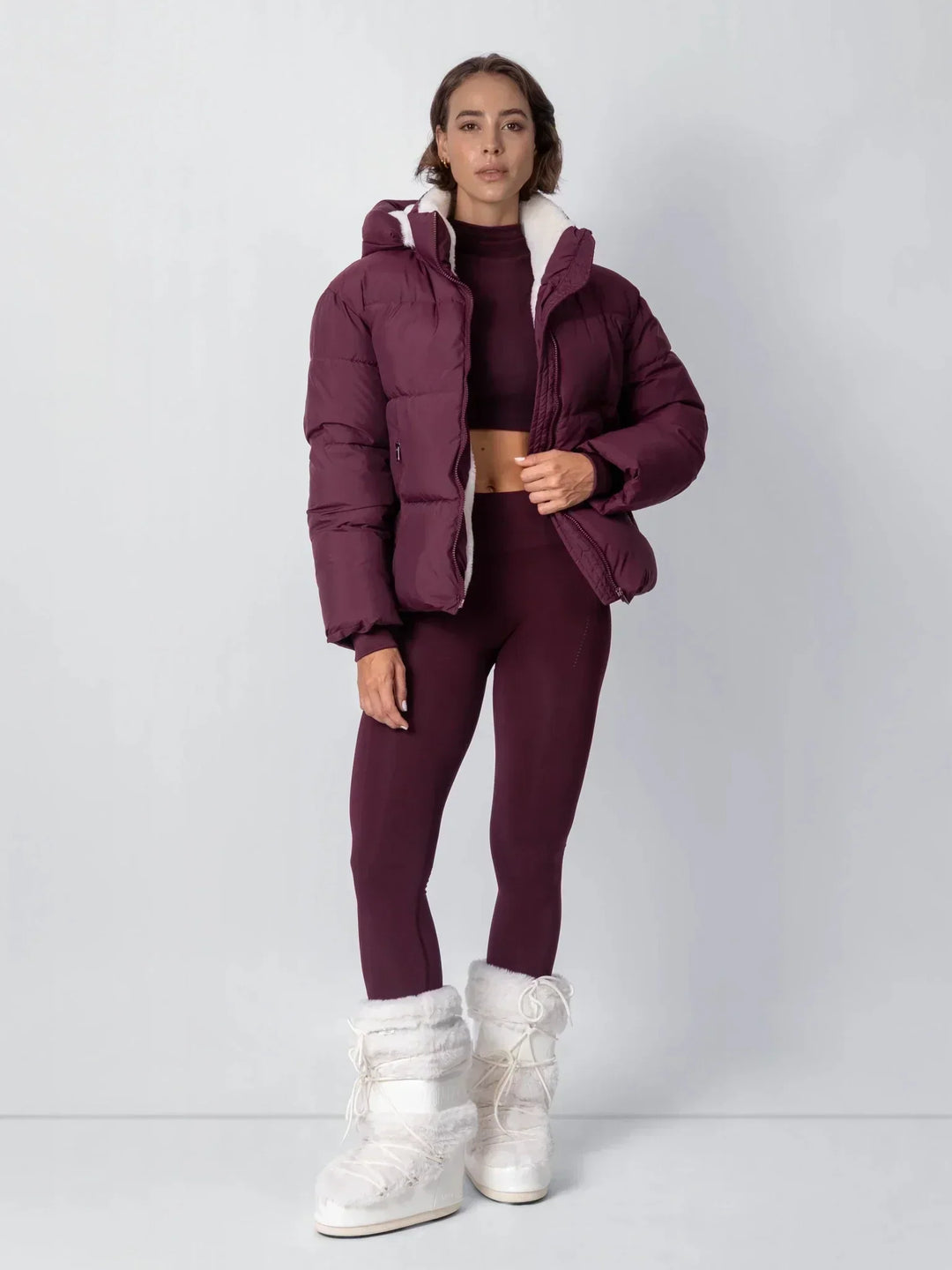 Ganzkörperansicht der bordeauxroten Steppjacke mit Leggings und weiĂźen flauschigen Winterstiefeln 17