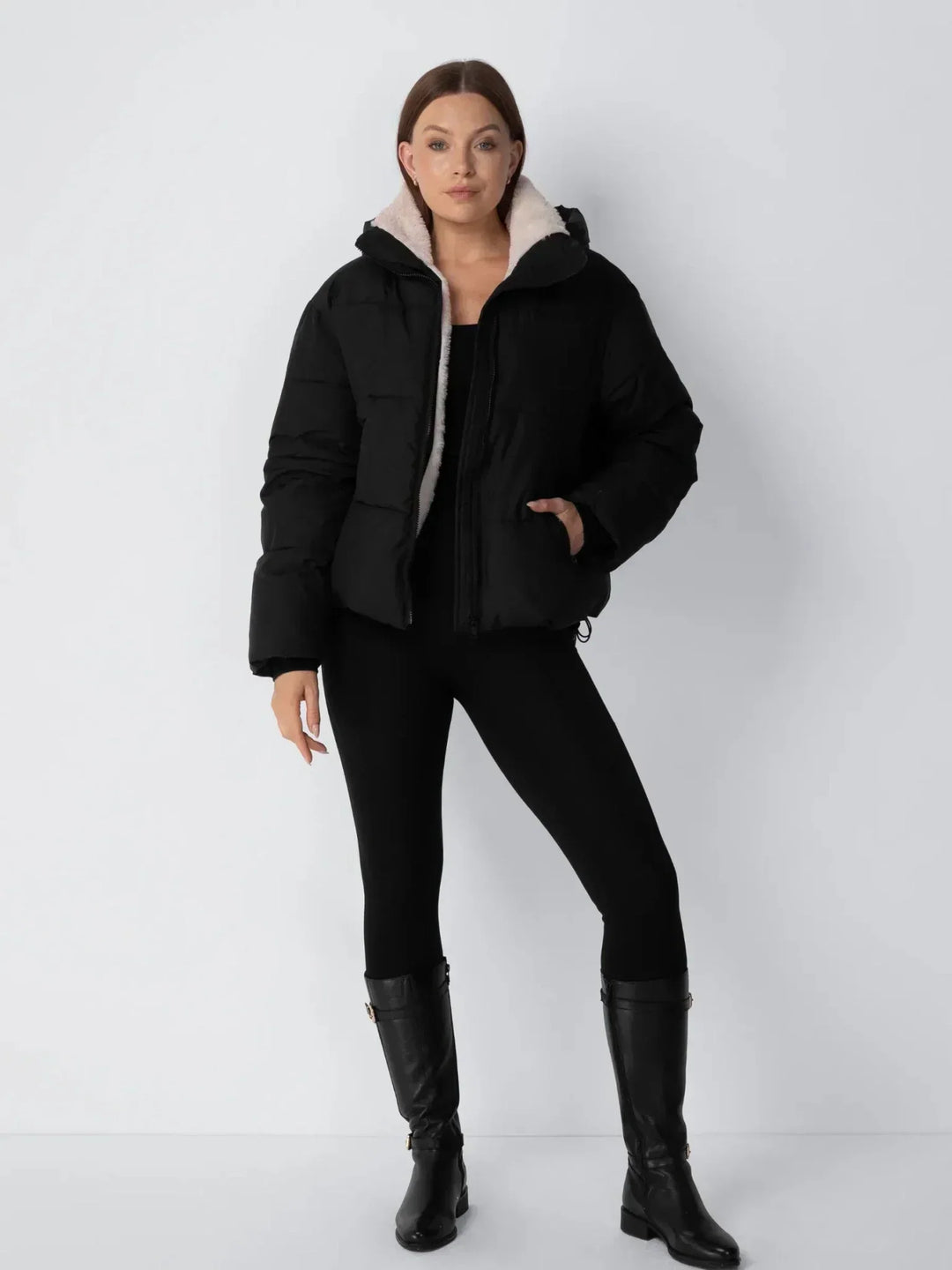 Ganzkörperansicht der schwarzen Steppjacke mit hellem Futter, kombiniert mit schwarzer Leggings und hohen Stiefeln 13