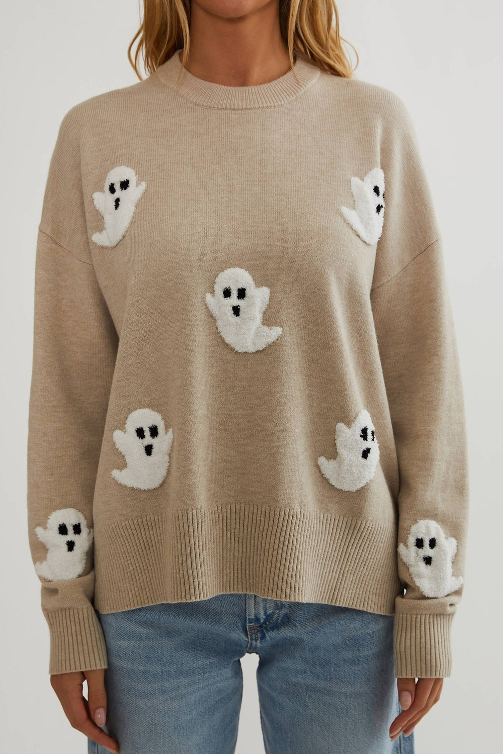 Nahaufnahme der Vorderseite des beigen Strickpullovers mit flauschigen weißen Geistern, Rippbündchen am Saum und an den Ärmeln. 2
