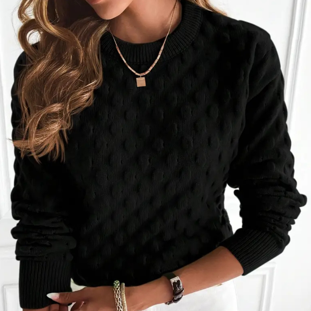 Frau in schwarzem Strickpullover mit Punktmuster, goldene Halskette, modisch, elegant.