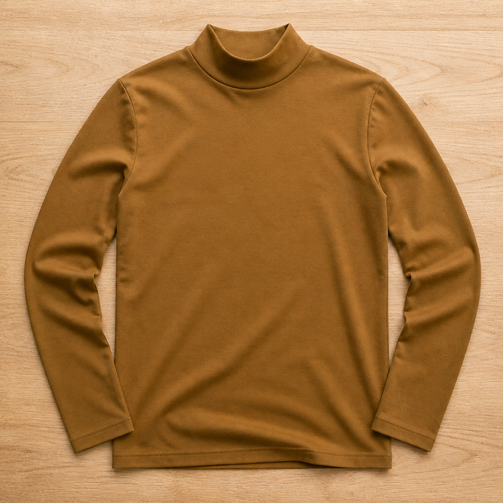 Braunes, senffarben wirkendes Langarmshirt mit hohem Kragen liegt in der Draufsicht auf einem Holzboden. 9